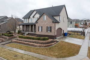 View of front of property with covered porch, a front yard, and a garage