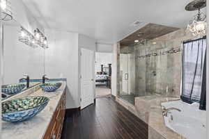 Bathroom with vanity, wood-type flooring, a textured ceiling, and shower with separate bathtub