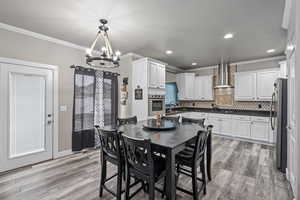 Dining area featuring sink, light wood-type flooring, ornamental molding, and an inviting chandelier