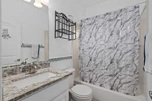 Full bathroom featuring shower / bath combo with shower curtain, vanity, and toilet