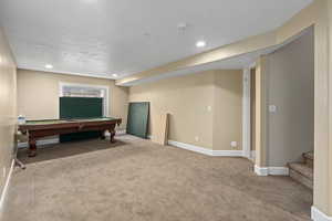 Recreation room with a textured ceiling, light carpet, and pool table