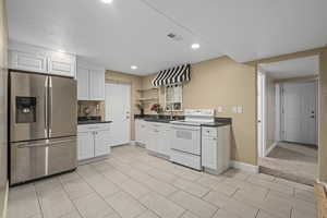 Kitchen with light carpet, sink, stainless steel fridge, white electric range oven, and white cabinetry