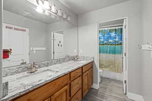 Full bathroom featuring toilet, vanity, shower / bath combo, and hardwood / wood-style flooring