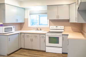 Kitchen with new hardwood-style flooring, white appliances, and ample counter space