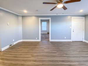 Bright living room with crown molding, a new ceiling fan, and updated flooring