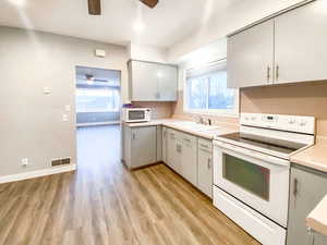 Kitchen featuring new light fixtures, white appliances, and new flooring