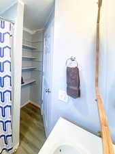 Bathroom with shelving for plenty of storage, new light hardwood / wood-laminate style flooring, and walk-in shower/tub combo