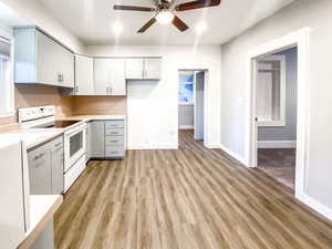 Kitchen with light gray cabinets, a new ceiling fan, white electric stove, and new light hardwood-style laminate flooring