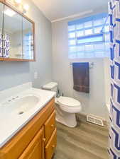 Full bathroom featuring new paint, new door, vanity, shower/bath combination with curtain, toilet, and new wood-type flooring