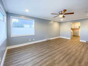 Living room boasts fresh paint, new windows, new blinds, a new ceiling fan, crown molding, and beautiful new light hardwood-style laminate flooring