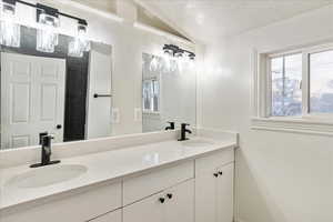 Bathroom featuring vanity, lofted ceiling, and a textured ceiling