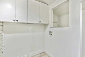 Laundry area with light hardwood / wood-style floors, cabinets, a textured ceiling, and hookup for a washing machine