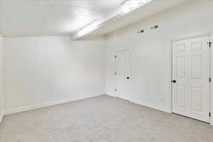 Empty room with light carpet, beamed ceiling, and a textured ceiling