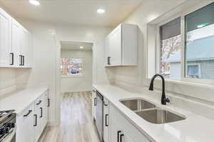 Kitchen featuring white cabinets, plenty of natural light, sink, and light hardwood / wood-style flooring