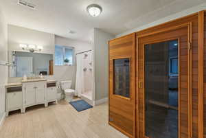 Bathroom featuring curtained shower, hardwood / wood-style floors, a textured ceiling, toilet, and vanity