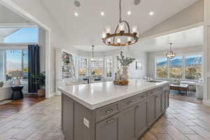 Kitchen with a wealth of natural light, sink, a kitchen island with sink, and a notable chandelier