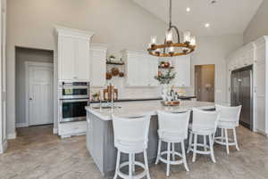 Kitchen featuring white cabinets, stainless steel appliances, and high vaulted ceiling