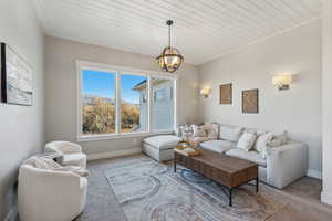 Living room with carpet floors, wooden ceiling, and a notable chandelier