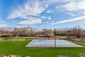 View of basketball court with a mountain view and a yard