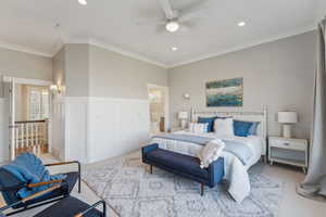 Carpeted bedroom with ceiling fan, ensuite bathroom, and crown molding