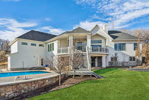 Back of property with a yard and a balcony