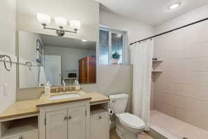 Bathroom featuring a shower with curtain, vanity, a textured ceiling, and toilet