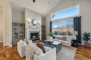 Living room with a mountain view, dark hardwood / wood-style flooring, high vaulted ceiling, and a fireplace