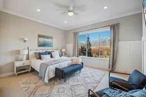 Bedroom with a mountain view, crown molding, ceiling fan, and light carpet