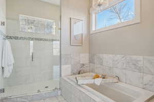 Bathroom featuring an inviting chandelier, a wealth of natural light, and independent shower and bath