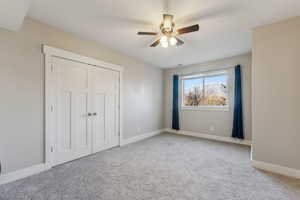 Unfurnished bedroom featuring ceiling fan, light colored carpet, and a closet