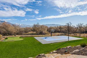 View of basketball court featuring a mountain view and a lawn