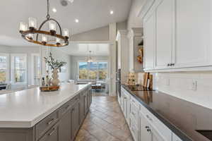 Kitchen with lofted ceiling, sink, tasteful backsplash, a large island, and a chandelier