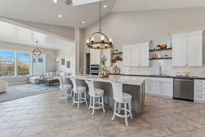 Kitchen featuring white cabinets, sink, hanging light fixtures, appliances with stainless steel finishes, and tasteful backsplash