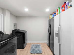 Washroom featuring separate washer and dryer, light hardwood / wood-style flooring, and electric panel