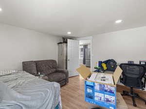 Bedroom with stainless steel refrigerator and light hardwood / wood-style flooring