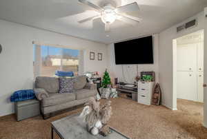 Carpeted living room featuring a textured ceiling and ceiling fan