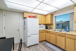 Kitchen featuring sink, white appliances, and light wood-type flooring