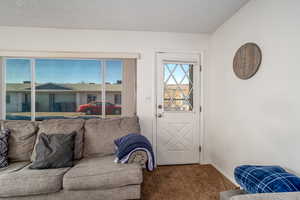 Doorway to outside featuring carpet flooring and a textured ceiling