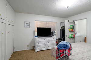 Bedroom with washing machine and dryer, carpet, and a textured ceiling