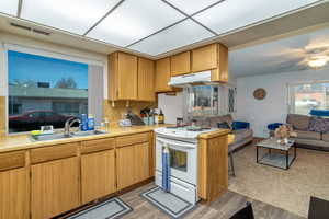 Kitchen featuring sink, light hardwood / wood-style flooring, ceiling fan, tasteful backsplash, and white range with electric stovetop