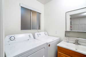 Washroom featuring washing machine and clothes dryer, sink, and a textured ceiling