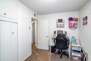 Office space with carpet flooring and a textured ceiling