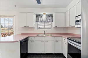 Kitchen featuring kitchen peninsula, appliances with stainless steel finishes, ceiling fan, sink, and white cabinets