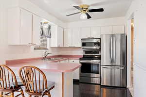 Kitchen featuring white cabinets, stainless steel appliances, kitchen peninsula, and sink