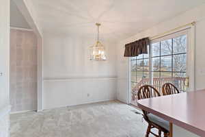 Dining space featuring light carpet and a notable chandelier