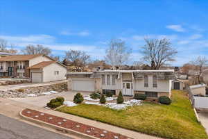 Split foyer home featuring a front lawn and a garage