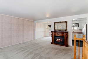 Unfurnished living room featuring ceiling fan, light colored carpet, and sink