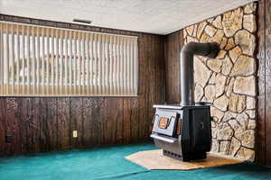 Room details featuring carpet, a wood stove, and wooden walls