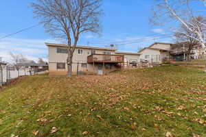 Rear view of house featuring a lawn and a wooden deck