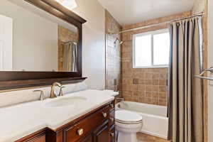 Full bathroom with tile patterned floors, vanity, shower / bath combination with curtain, and toilet